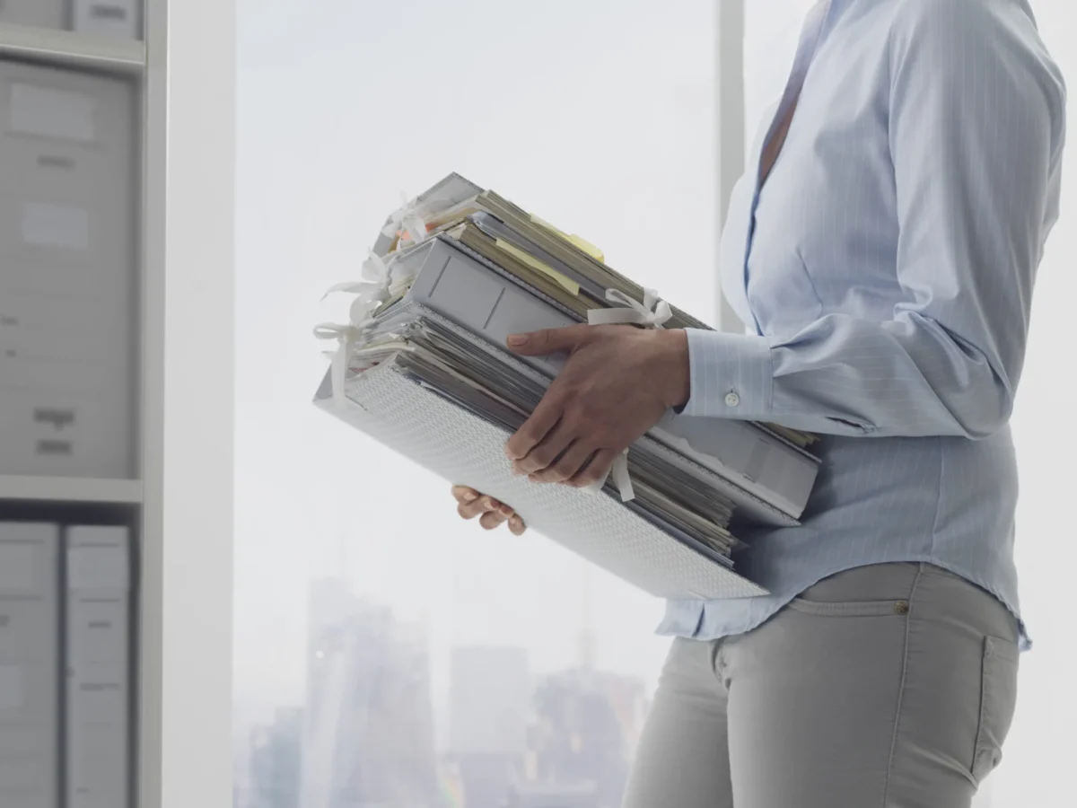 profile of person carrying multiple folders in an office setting