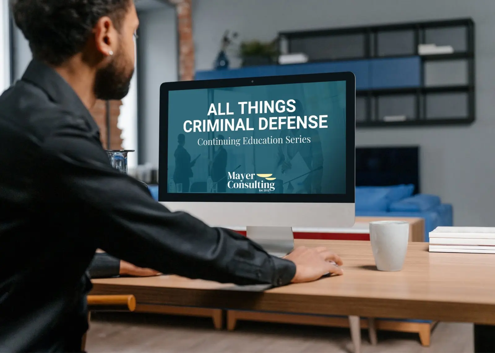 Investigator at a desk watching an All Things Criminal Defense continuing education session on screen